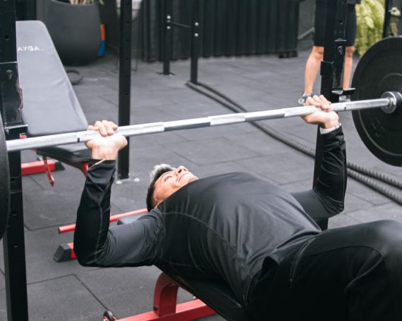 Adult man performing bench press exercise in a gym in Mexico City, emphasizing strength and fitness.